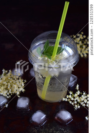 Homemade elderflower lemonade with lemon and elderberry flowers in plastic cup with sphere dome cap and cocktail tube. Elderflower cordial. Summer cold drink 128531599