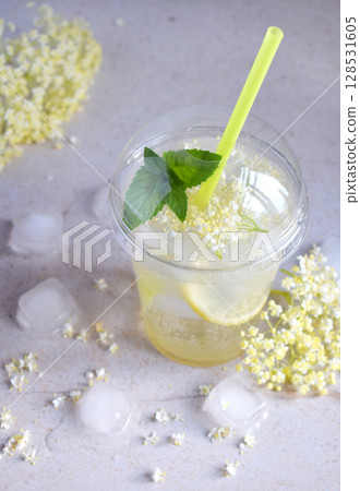 Homemade elderflower lemonade with lemon and elderberry flowers in plastic cup with sphere dome cap and cocktail tube. Elderflower cordial. Summer cold drink 128531605