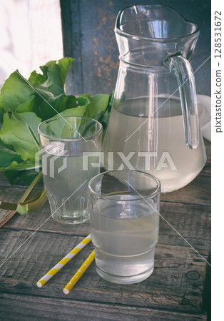 Refreshing healthy summer drink with rhubarb. Pieplant lemonade in glass on wooden background. Homemade rhabarbarum compote. 128531672