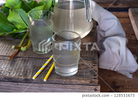 Homemade refreshing drink with rhubarb. Iced juice in glass on wooden background. Homemade refreshing drink with rhubarb. Iced juice in glass on wooden background. 128531673