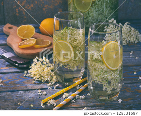 Elderberry flowers and lemon drink. Refreshing healthy summer juice. Glass of elderflower lemonade on wooden rustic board. Alternative medicine and therapy. 128531687
