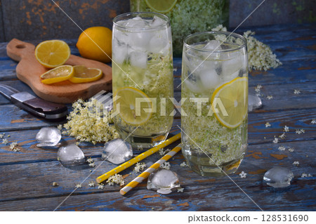 Elderberry flowers and lemon drink. Refreshing healthy summer juice. Glass of elderflower lemonade on wooden rustic board. Alternative medicine and therapy. 128531690