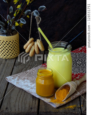Turmeric powder, paste and latte on wooden background. Ayurvedic healthy golden drink with coconut milk and ghee for beauty and health. Selective focus. Copy space 128531751