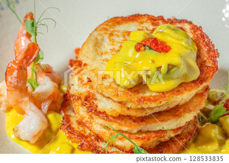 Crispy potato pancakes stacked with creamy yellow curry sauce, garnished with shrimp, herbs, and red caviar pearls Crispy potato pancakes stacked with creamy yellow curry sauce, garnished with shrimp, herbs, and red caviar pearls 128533835