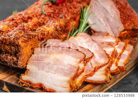 Close-up of juicy sliced pork belly with a spicy red crust, showcasing its marbled texture and rich seasoning on a rustic wooden board Close-up of juicy sliced pork belly with a spicy red crust, showcasing its marbled texture and rich seasoning on a rustic wooden board 128533986