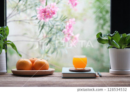 Raw oranges and orange juice with pink flowers background Raw oranges and orange juice with pink flowers background 128534532