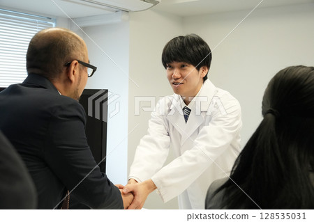 一名男子與一名穿白大褂的醫生握手 一名男子與一名穿白大褂的醫生握手 128535031