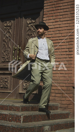 Man in vintage outfit walking down stairs in urban setting Man in vintage outfit walking down stairs in urban setting 128535283