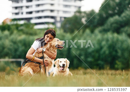 Sitting on the ground. Woman with beautiful dogs are in the field outdoors Sitting on the ground. Woman with beautiful dogs are in the field outdoors 128535397
