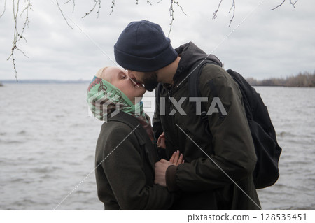 Portrait of man and young blond woman couple hugging each other kissing at seaside Portrait of man and young blond woman couple hugging each other kissing at seaside 128535451