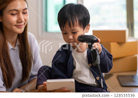 Sell Online: Young boy scanning items with mother in home office Sell Online: Young boy scanning items with mother in home office 128535536