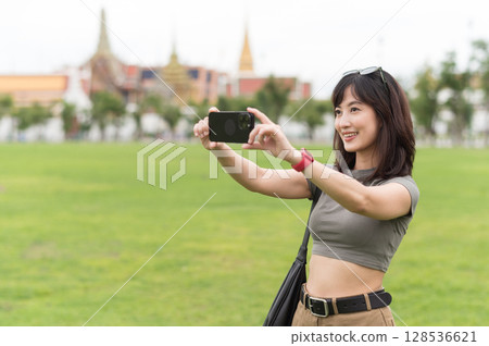 Happy southeast asian woman teenager blogger on solo world travel use smartphone to take photo. local cultural experience for tourism concept for an asia explorer in Bangkok Thailand 128536621