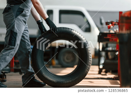 Rolling the wheel. Man is works in the automobile repairing salon Rolling the wheel. Man is works in the automobile repairing salon 128536865