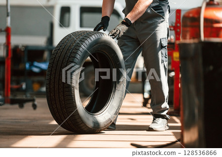 Rolling the wheel. Man is works in the automobile repairing salon Rolling the wheel. Man is works in the automobile repairing salon 128536866