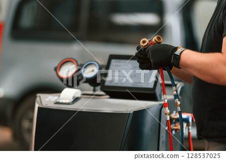 With wires in hands. Man is works in the automobile repairing salon 128537025