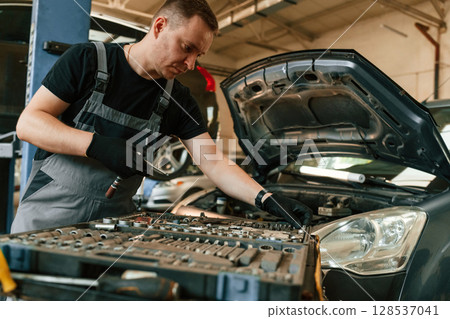 Under the hood. Man is works in the automobile repairing salon 128537041