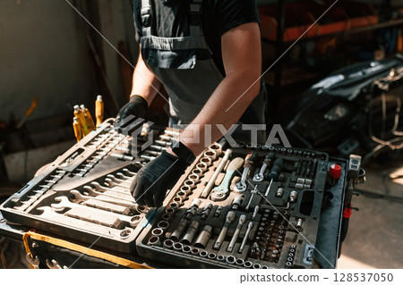 Tools for the repair in the box. Man is works in the automobile salon Tools for the repair in the box. Man is works in the automobile salon 128537050
