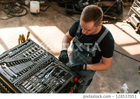 Tools for the repair in the box. Man is works in the automobile salon Tools for the repair in the box. Man is works in the automobile salon 128537051