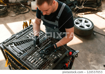 Standing by the toolbox. Man is works in the automobile repairing salon Standing by the toolbox. Man is works in the automobile repairing salon 128537053