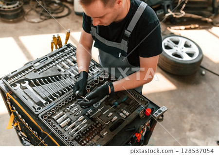 Standing by the toolbox. Man is works in the automobile repairing salon 128537054