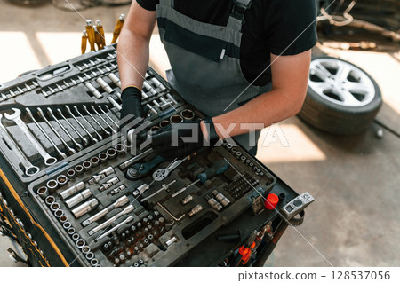 Standing by the toolbox. Man is works in the automobile repairing salon 128537056