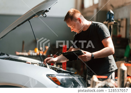 Using the tablet. Man is works in the automobile repairing salon 128537057