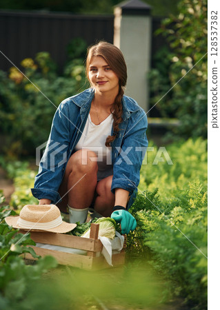 Cheerful, looking at camera. Beautiful young woman is gardening Cheerful, looking at camera. Beautiful young woman is gardening 128537382