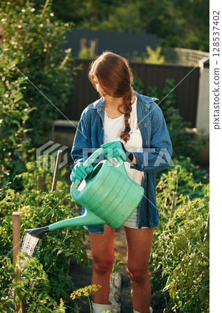 Watering the plants. Beautiful young woman is gardening Watering the plants. Beautiful young woman is gardening 128537402