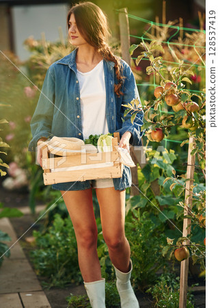 Confident worker with wooden box. Beautiful young woman is gardening 128537419