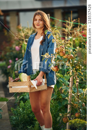 Confident worker with wooden box. Beautiful young woman is gardening 128537426