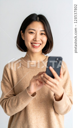 Smiling woman holding a smartphone Smiling woman holding a smartphone 128537802