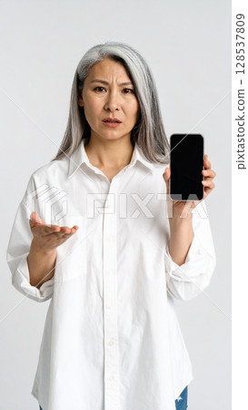 一名女子手持智慧型手機，表情憤怒 128537809