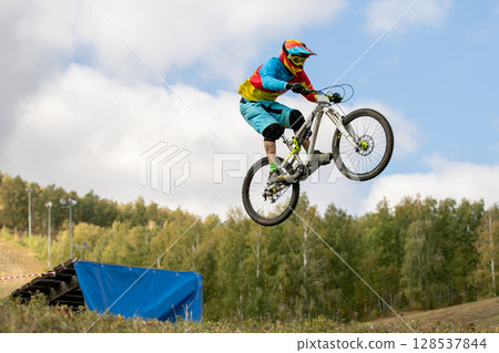 mountain biker jump springboard on downhill competition race 128537844