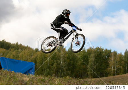 mountain biker jumping springboard on during downhill competition mountain biker jumping springboard on during downhill competition 128537845