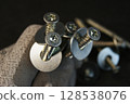 Construction work process. Construction worker holding large bolts with washers.  128538076