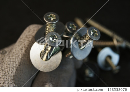 Construction work process. Construction worker holding large bolts with washers. Construction work process. Construction worker holding large bolts with washers. 128538076
