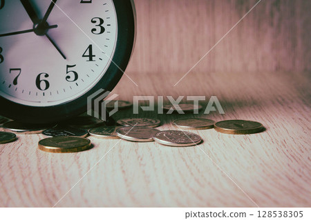 Alarm clock and money. Time is money. Coins on the background of the clock. Alarm clock and money. Time is money. Coins on the background of the clock. 128538305