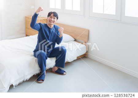 Smiling man doing fist pump in bed 128538724