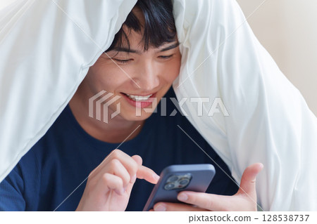 男人在床上使用智慧型手機 128538737