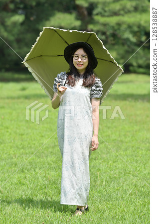A young lady walking with a parasol 128538887