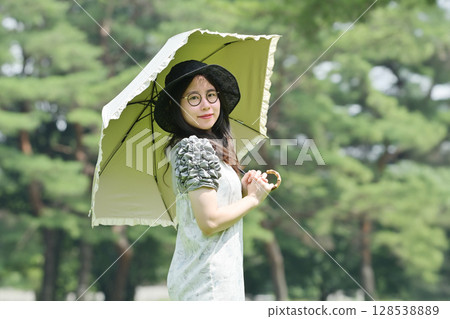 A young lady walking with a parasol 128538889