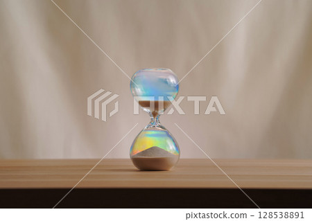 A simple hourglass on a wooden table with a beige backdrop, symbolizing time flow and minimalistic living. Running out of time, uncluttered presentation for stylish concepts. A simple hourglass on a wooden table with a beige backdrop, symbolizing time flow and minimalistic living. Running out of time, uncluttered presentation for stylish concepts. 128538891