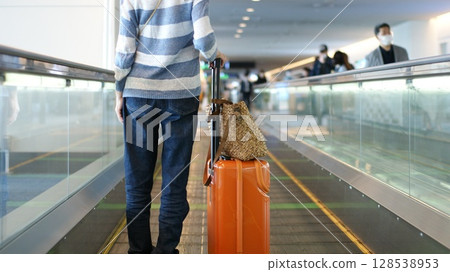 一名女子在機場自動人行道上行走 一名女子在機場自動人行道上行走 128538953