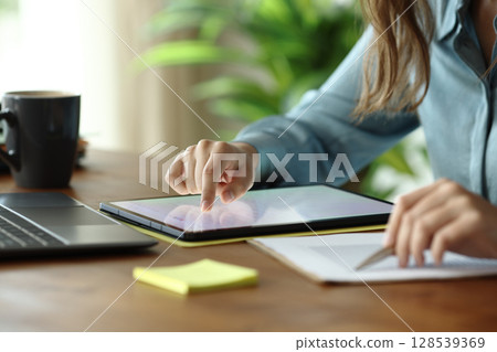 Office worker scrolling on tablet checking statistics on document 128539369