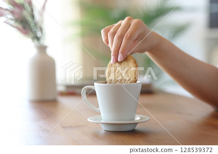Woman hand dipping cookie on coffee at home 128539372