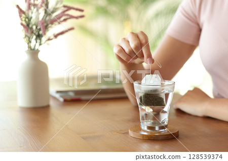 Woman hand prepating tea with a bag at home Woman hand prepating tea with a bag at home 128539374