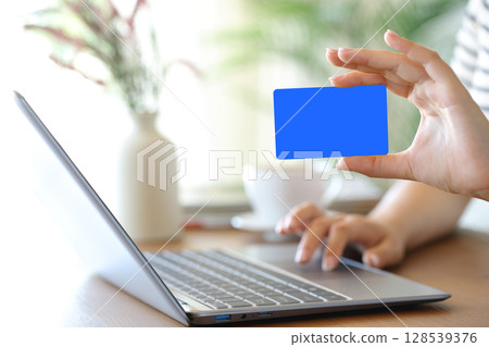 Woman hand showing blank card using laptop 128539376