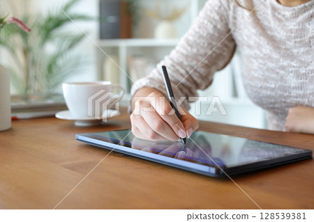 Woman hands drawing or handwriting with digital pen on tablet Woman hands drawing or handwriting with digital pen on tablet 128539381