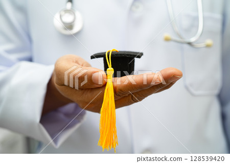Asian woman doctor holding graduation hat in hospital, Medical education. 128539420