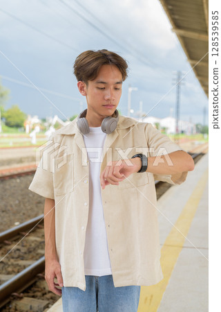 Young non binary tourist traveler in train station using smartwatch 128539585